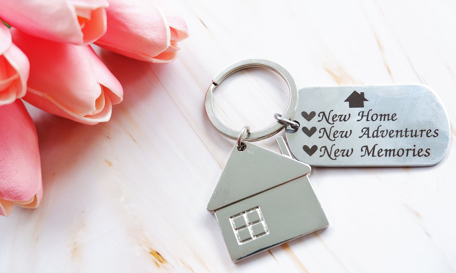 House keychain with engraved plaque and pink roses on marble counter
